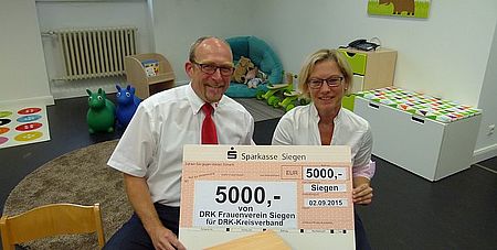 Die Vorsitzende des DRK-Frauenverein Siegen, Sylvia Schürg, übergab Kreisgeschäftsführer Ralf Henze einen Spendenscheck in Höhe von 5000 Euro für den Umbau der alten Aula im Henry-Dunant-Haus