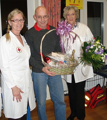 Hans-Werner Bachmann (Mitte) erhält von Marita Hapke (Blutspendebeauftragte DRK-Frauenverein Siegen) und Frau Liermann (Teamleiterin Blutspendedienst West) für sein 165. Blutspende einen Blumenstrauß und einen Präsentkorb