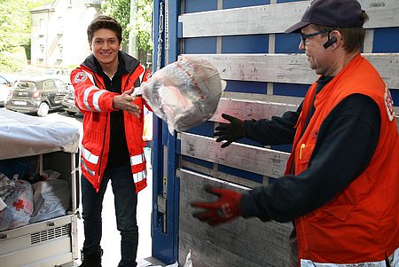 Vl. Rotkreuzler Niklas Benndorf und Wolfgang Müller des DRK-Ortsvereins Siegen-Mitte beim Entladen der Kleiderspenden auf einen bereitgestellten LKW an der Siegener Eintracht. Bild:  DRK-Kreisverband Siegen-Wittgenstein e.V.