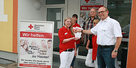 Ralf Henze (Kreisgeschäftsführer) übergibt Christine Renard den Haustürschlüssel für das neue Beratungsbüro des DRK in der Wildrosenallee 1 in Siegen-Geisweid.