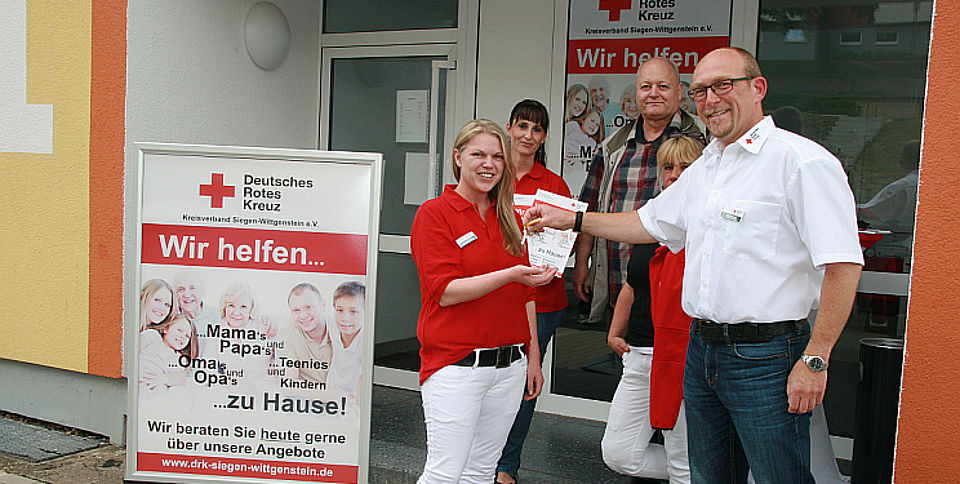 Ralf Henze (Kreisgeschäftsführer) übergibt Christine Renard den Haustürschlüssel für das neue Beratungsbüro des DRK in der Wildrosenallee 1 in Siegen-Geisweid.