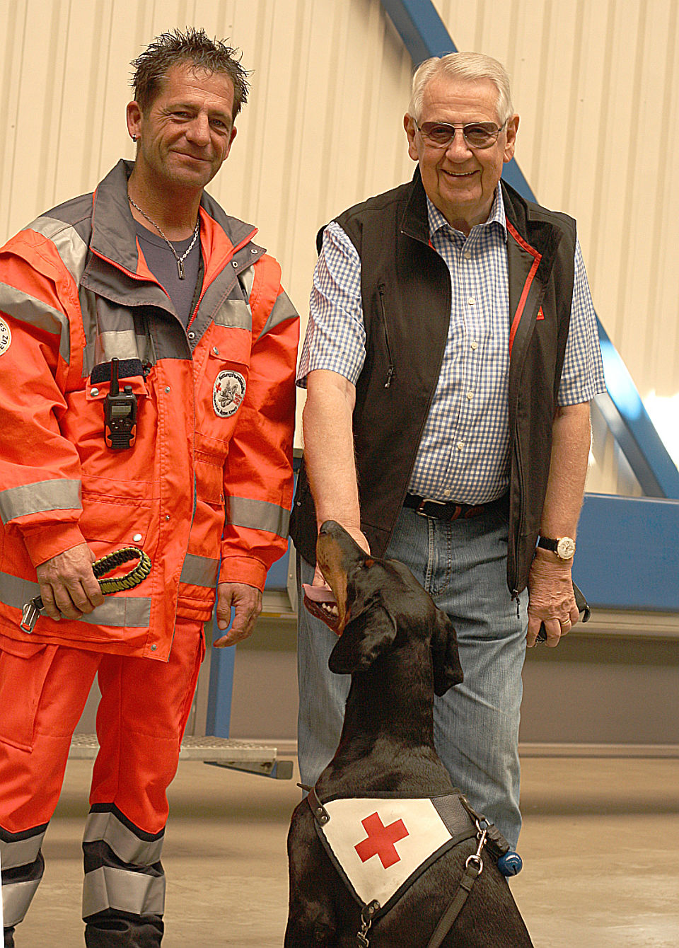 Unternehmer Klaus Vetter (rechts) unterstützt gerne das ehrenamtliche Engagement seiner Mitarbeiter wie Roger Merte (links), der sich mit seiner Dobermannhündin Chandra zurzeit intensiv auf die Einsatzprüfung zum DRK-Rettungshundeteam vorbereitet und mit den Kameraden der Siegen-Wittgensteiner DRK-Rettungshundestaffel an seinem Arbeitsplatz trainieren durfte.