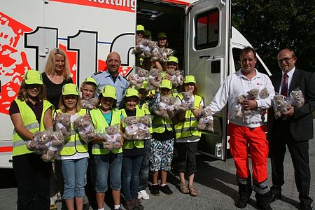 vl: Lehrerin Hannah Weissiger und Polizist Ralf Möckel (hinten), übergeben gemeinsam mit den Schülern der Stahlbergschule insgesamt 50 Rettungsteddys an Detlef Klein (stellv. Wachleiter der Rettungswache Kreuztal) und Ralf Henze (DRK-Kreisgeschäftsführer)