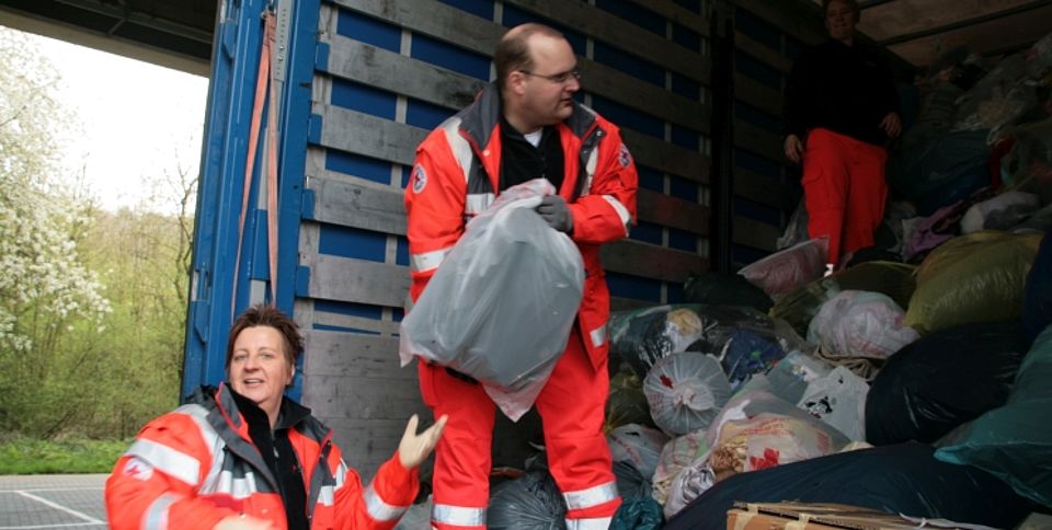 Vl. DRK-Helfer Evelyn Trapp, Jörg Büdenbender und Brigitte Flegler des Ortsvereins Siegen-Nord, beim Entladen der Kleiderspenden auf einen bereitgestellten LKW.